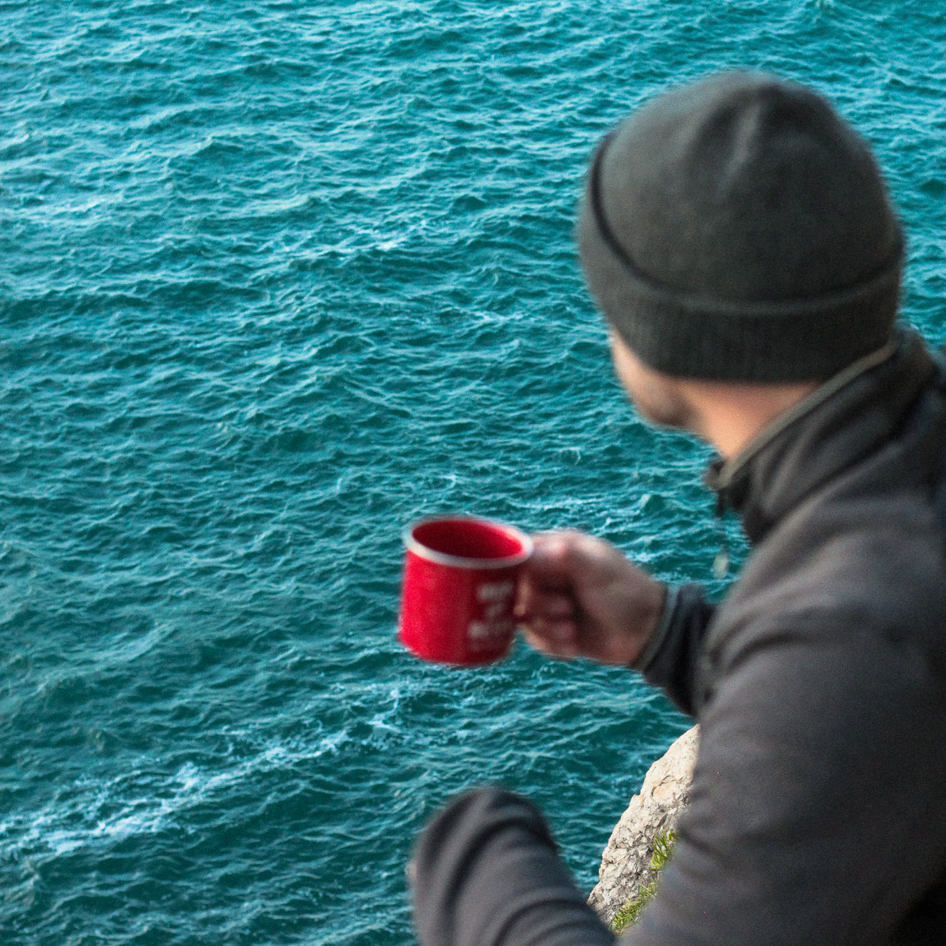 aventurier buvant une tasse de café bio COOKNRUN devant l'océan