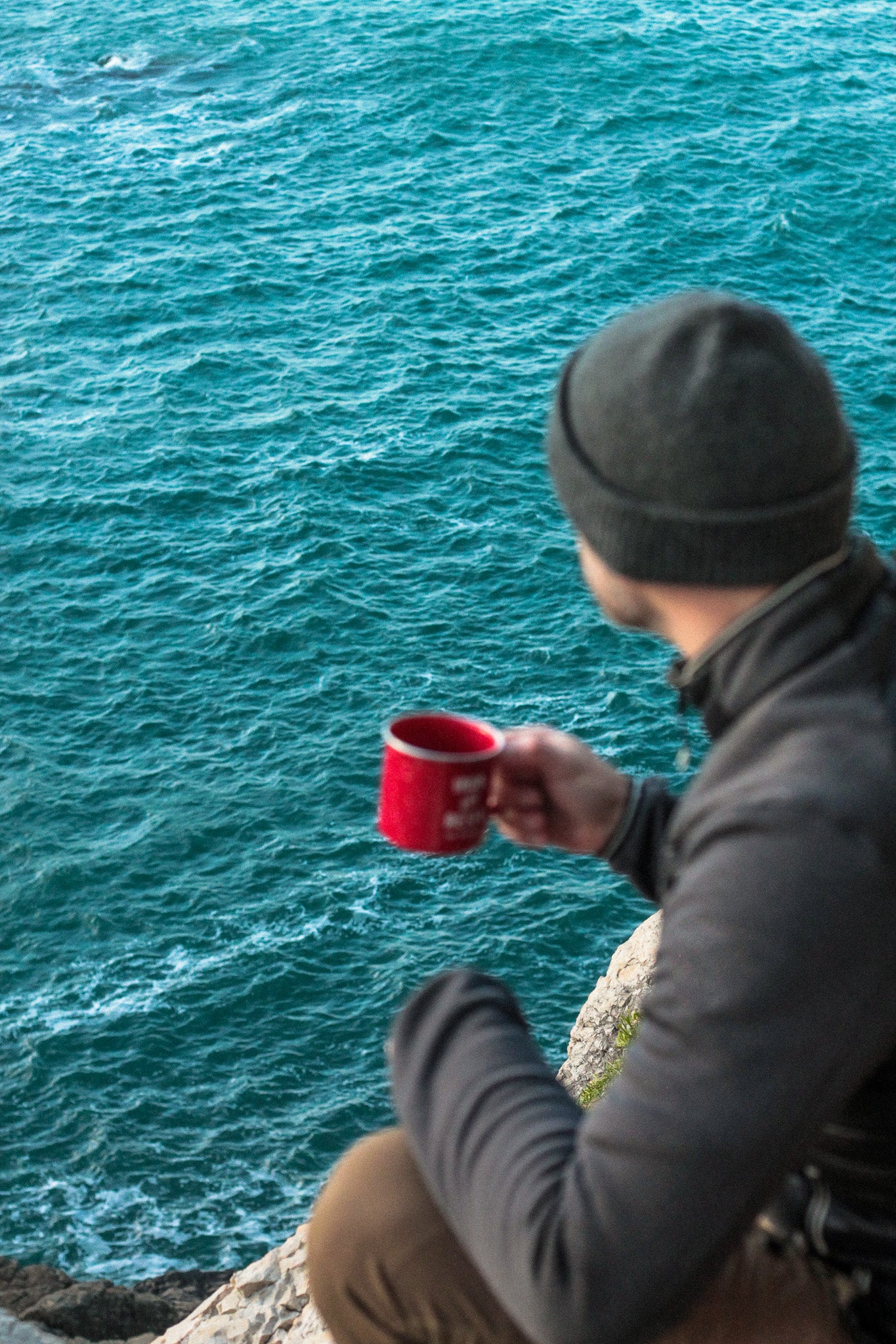 aventurier buvant une tasse de café bio COOKNRUN devant l'océan