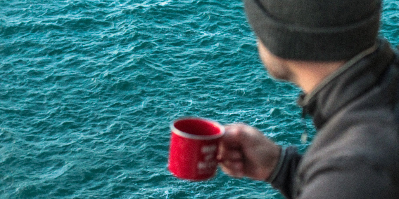 aventurier buvant une tasse de café bio COOKNRUN devant l'océan